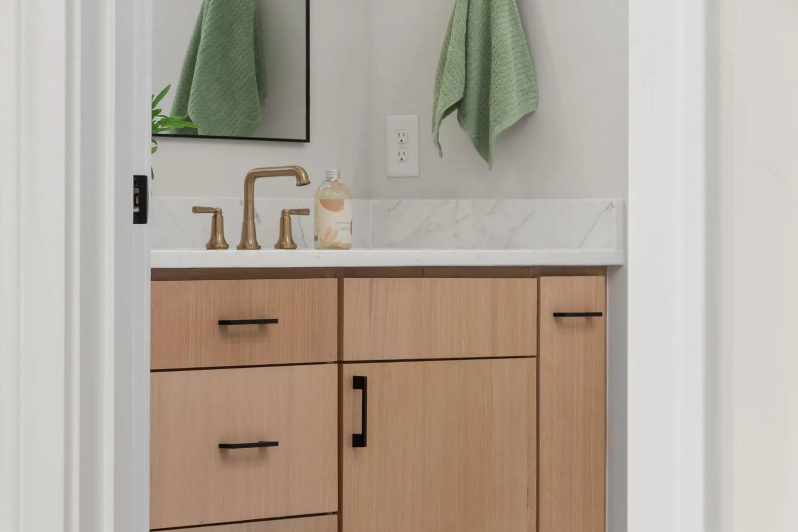 Ambiente de inspiración: mueble de baño de madera clara con encimera blanca y grifería dorada